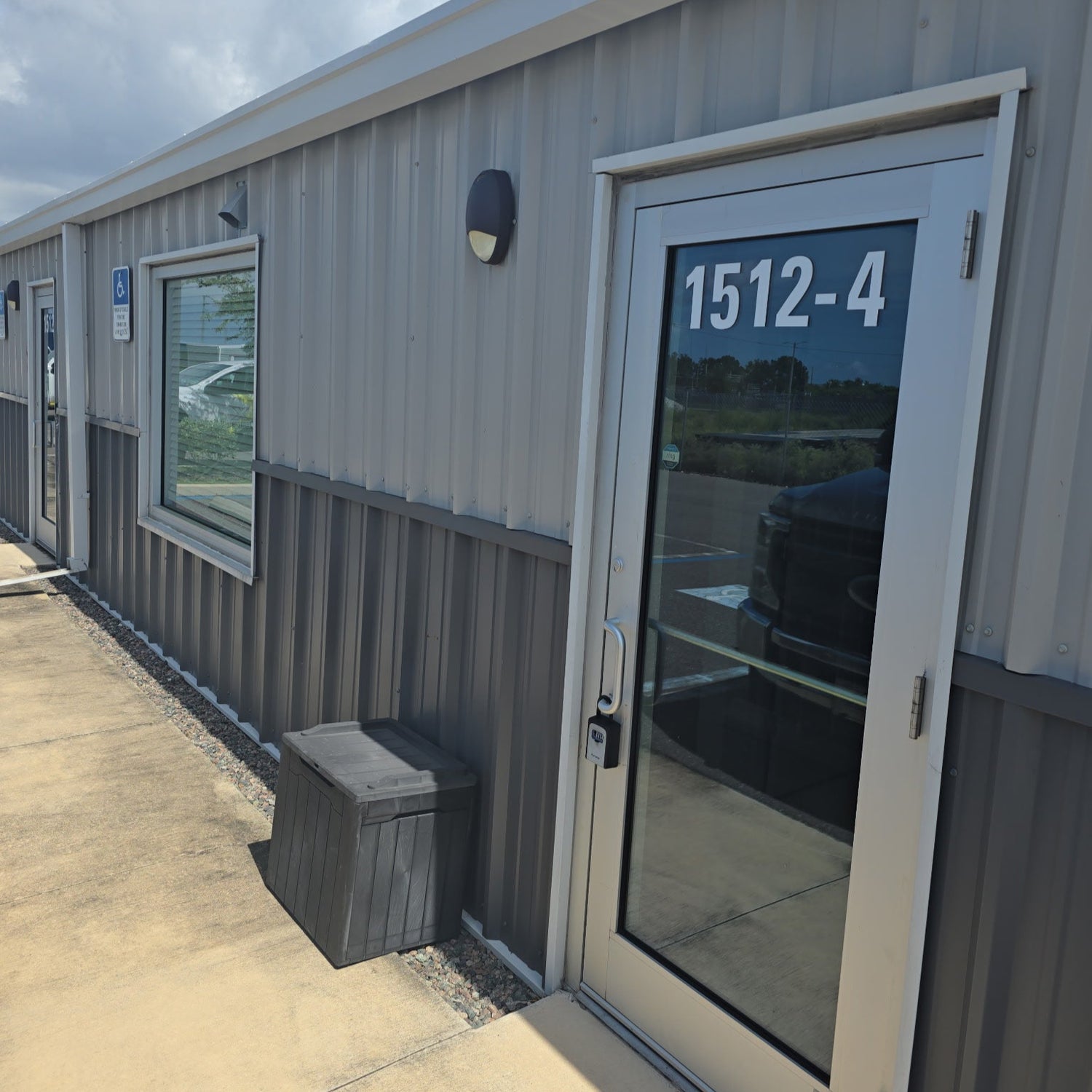 Metal storage building with a door number '1512-4' on a cloudy day.
